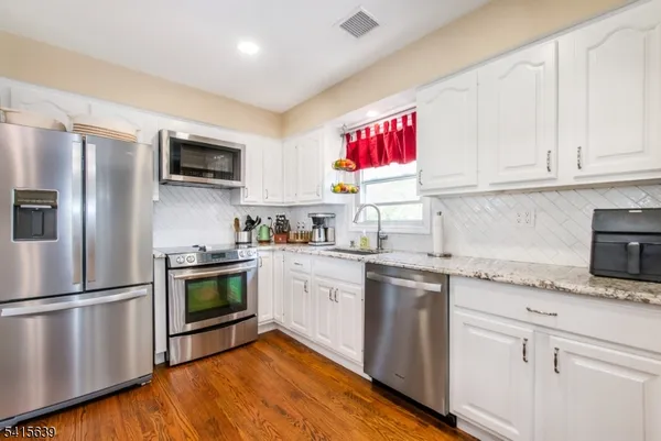 a kitchen with granite countertop stainless steel appliances a sink cabinets and a window