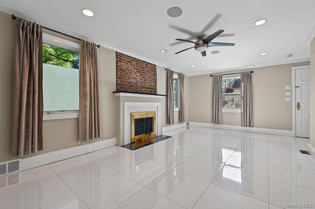 155 White Road Scarsdale, NY 10583 - Photo 12 of 30 a view of a livingroom with a ceiling fan a flat screen tv and a large window with stainless steel appliances
