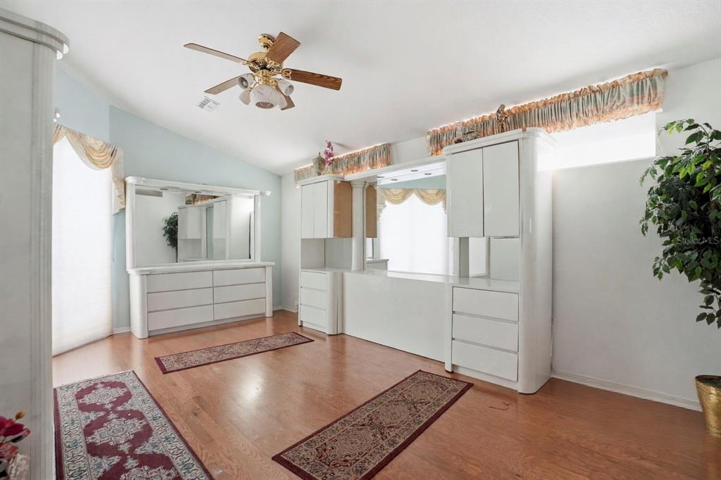 12054 Conway Street Spring Hill, FL 34609 - Photo 21 of 49 a view of a hallway to a bedroom with wooden floor and a ceiling fan