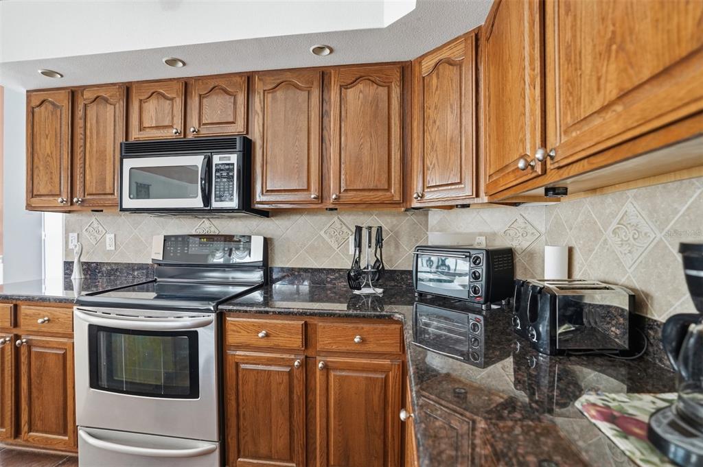 12054 Conway Street Spring Hill, FL 34609 - Photo 7 of 49 a kitchen with stainless steel appliances granite countertop a stove a sink and a microwave