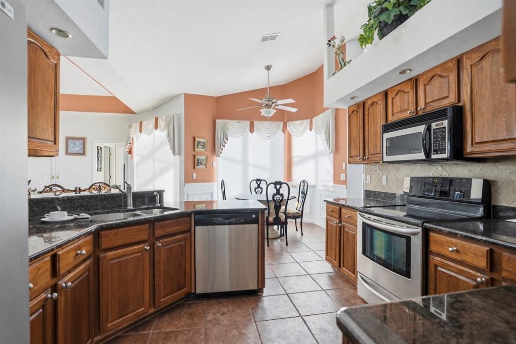 12054 Conway Street Spring Hill, FL 34609 - Photo 9 of 49 a kitchen with stainless steel appliances granite countertop a stove a sink and a microwave