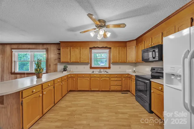 a large kitchen with stainless steel appliances granite countertop a refrigerator a sink dishwasher a stove with wooden cabinets and floor