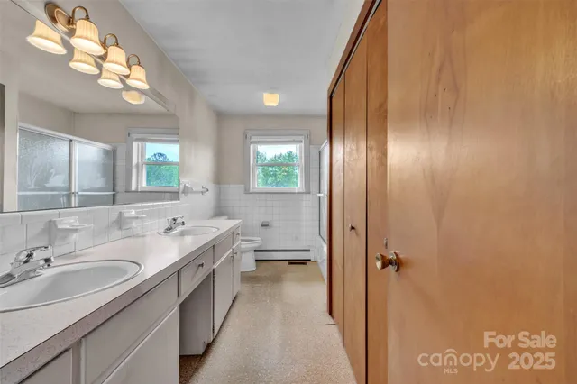 a bathroom with a double vanity sink and mirror with shower