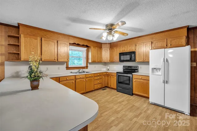 a large kitchen with stainless steel appliances granite countertop a stove a sink dishwasher a refrigerator with a dining table and chairs with wooden floor