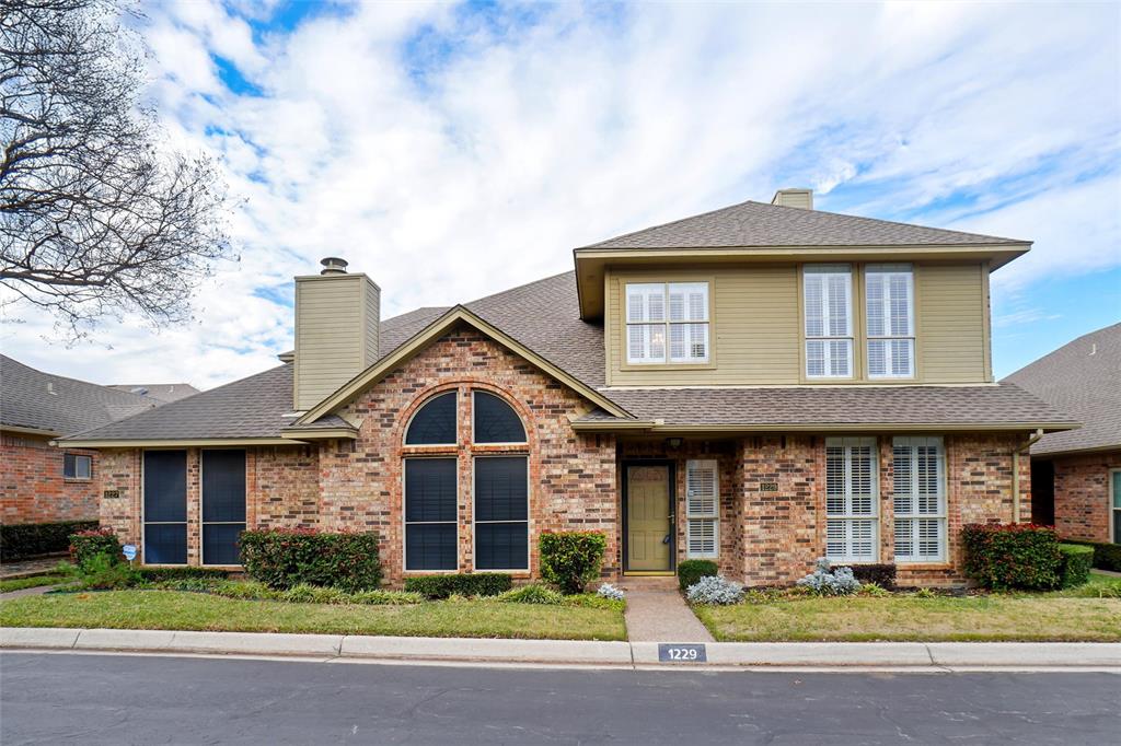 1229 Wooded Trail Hurst, TX 76053 - Photo 1 of 28 View of front facade featuring a chimney, brick siding, a shingled roof, and a front lawn