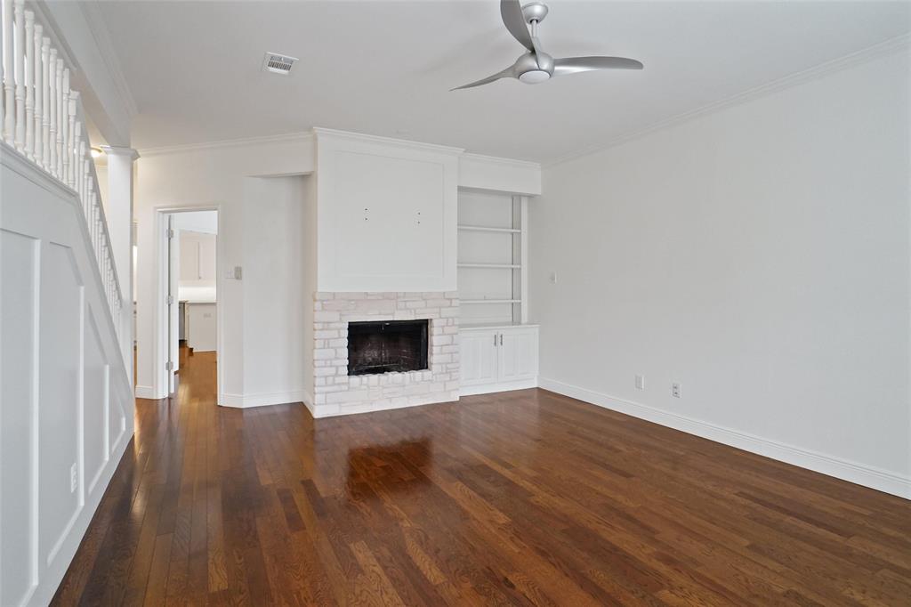 1229 Wooded Trail Hurst, TX 76053 - Photo 4 of 28 Unfurnished living room featuring crown molding, built in features, a brick fireplace, dark wood-type flooring, and ceiling fan
