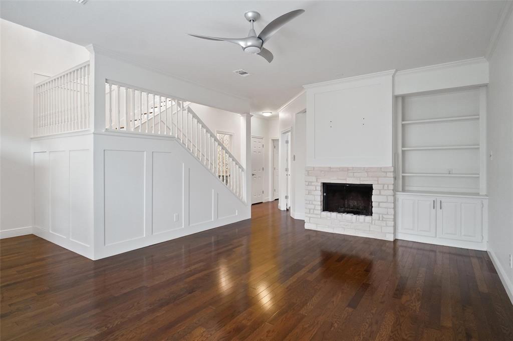 1229 Wooded Trail Hurst, TX 76053 - Photo 5 of 28 Unfurnished living room featuring built in features, stairway, dark wood-style flooring, ceiling fan, and a brick fireplace
