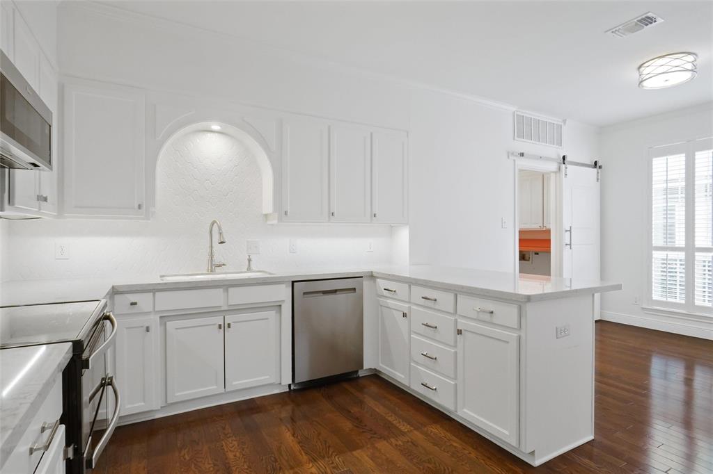 1229 Wooded Trail Hurst, TX 76053 - Photo 9 of 28 Updated Kitchen with white cabinetry, a peninsula, dark wood-type flooring, a barn door to utility room.