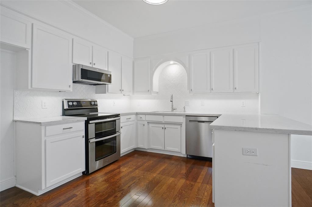 1229 Wooded Trail Hurst, TX 76053 - Photo 10 of 28 Kitchen featuring stainless steel appliances, white cabinetry, and breakfast bar