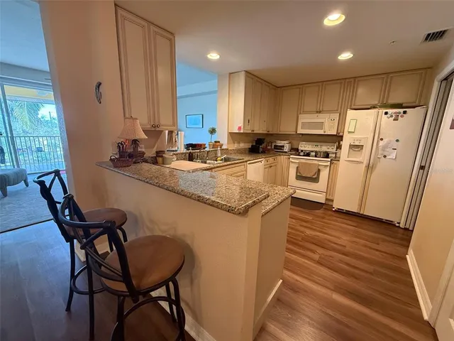 a kitchen with refrigerator a stove a sink and chairs