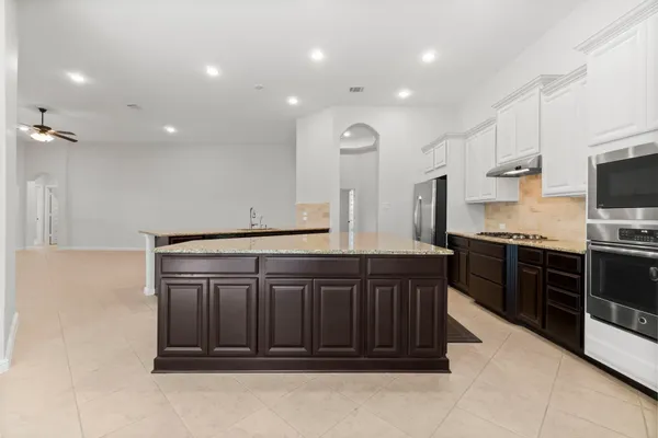 a large kitchen with stainless steel appliances granite countertop a stove a sink and a refrigerator