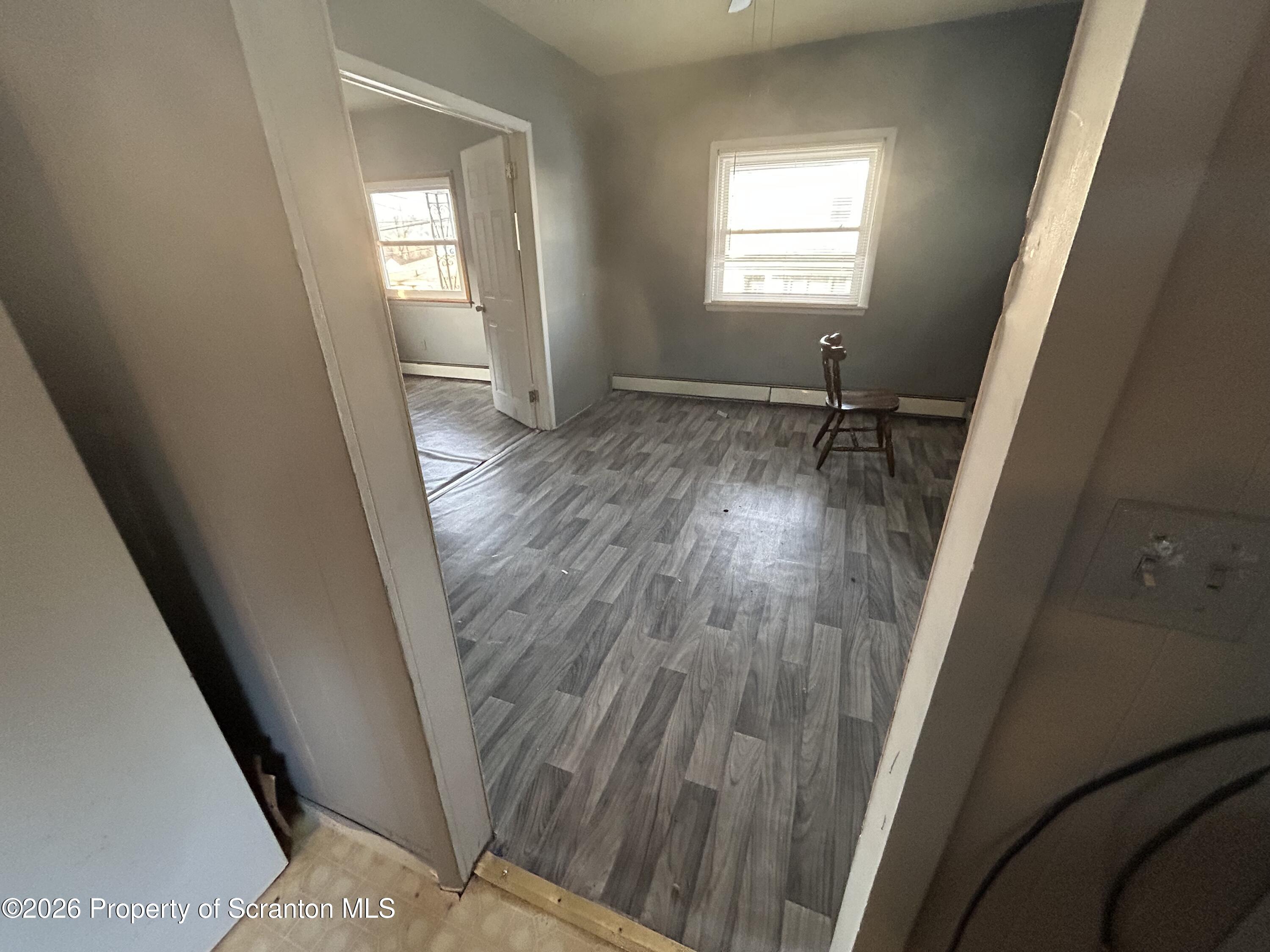 a view of empty room with wooden floor and fan