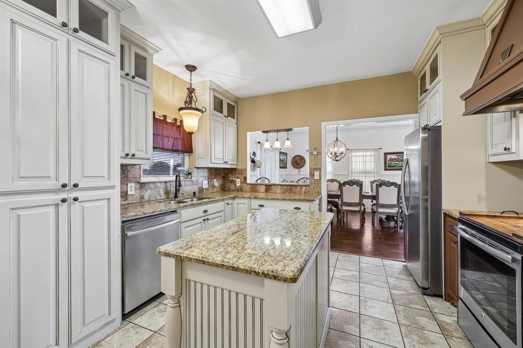 331 Radecke Road Krum, TX 76249 - Photo 18 of 40 Kitchen featuring a central island with granite countertop, white cabinetry with dark hardware, stainless steel appliances, and tile flooring