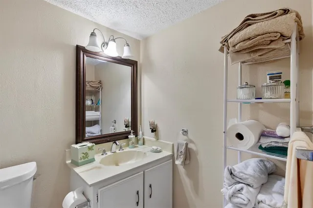 a bathroom with a granite countertop sink a toilet and mirror