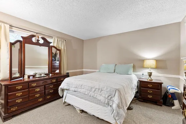 a bedroom with a bed a large window mirror and dresser