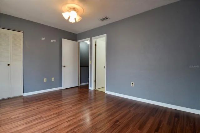 an empty room with wooden floor and a ceiling fan