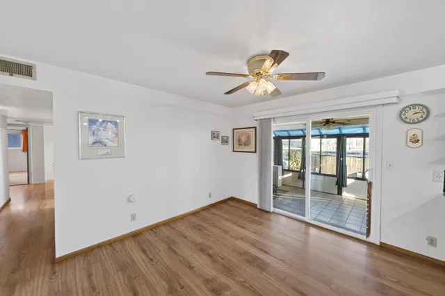 a view of an empty room with a window and wooden floor