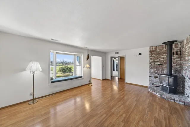 a view of an empty room with window and wooden floor