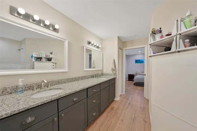 a spacious bathroom with a granite countertop double vanity sink a mirror and shower