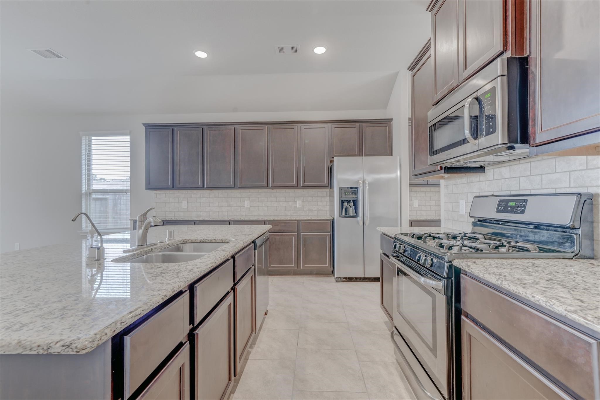 24311 North Newcastle Bay Trail Spring, TX 77389 - Photo 9 of 25 a kitchen with stainless steel appliances granite countertop a sink stove and refrigerator
