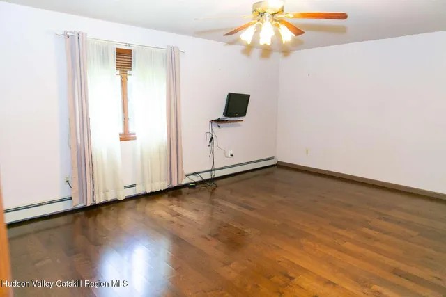 a view of an empty room with window and wooden floor