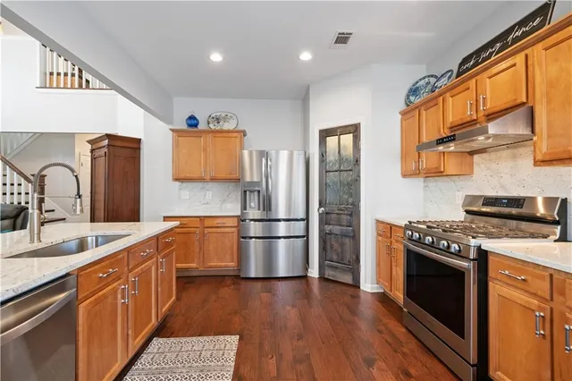 a kitchen with a refrigerator a sink and wooden floor