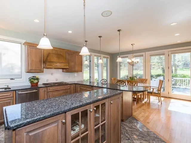 a kitchen with granite countertop a stove a sink a dining table and chairs with wooden floor