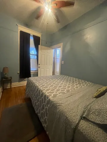 a bed sitting in a spacious bedroom next to a window and a chandelier