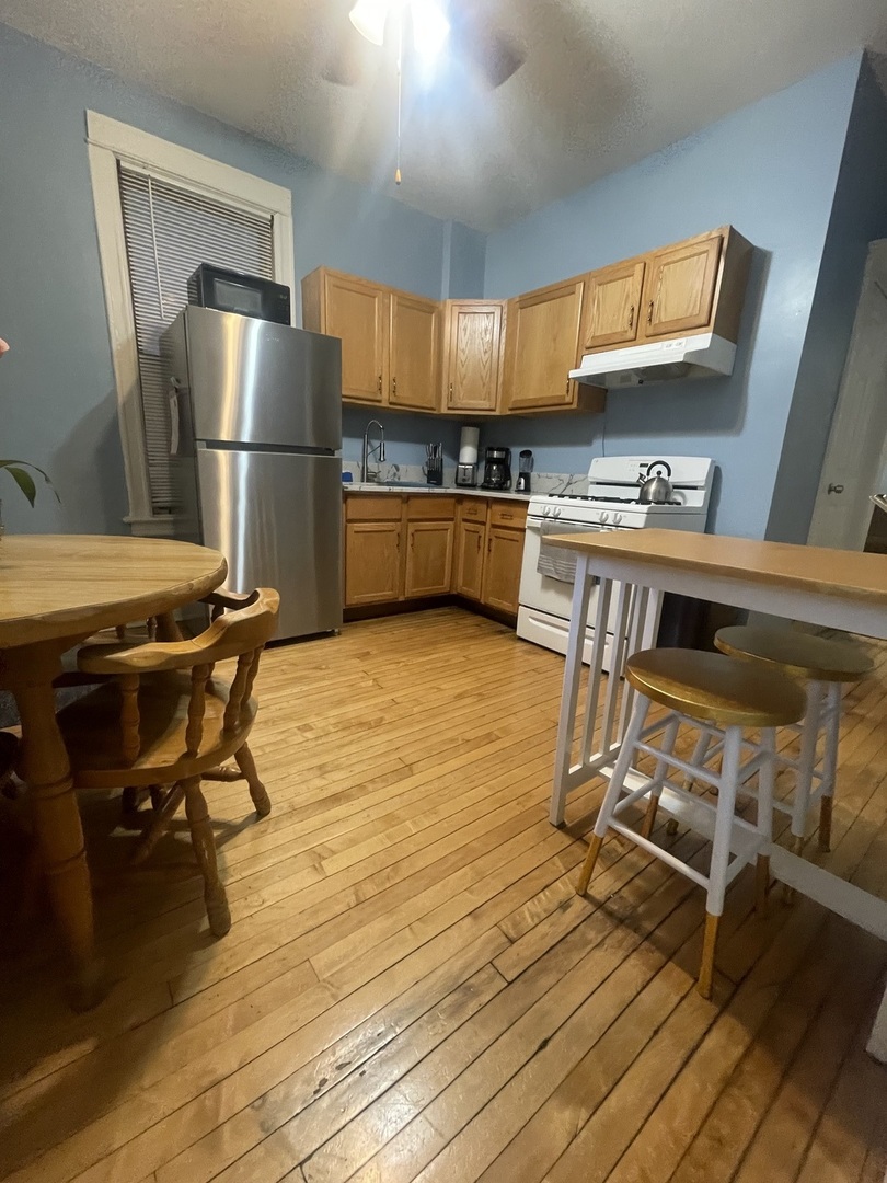 2107 West Coulter Street, Unit 1R Chicago, IL 60608 - Photo 4 of 26 a kitchen with a table chairs refrigerator and wooden floor