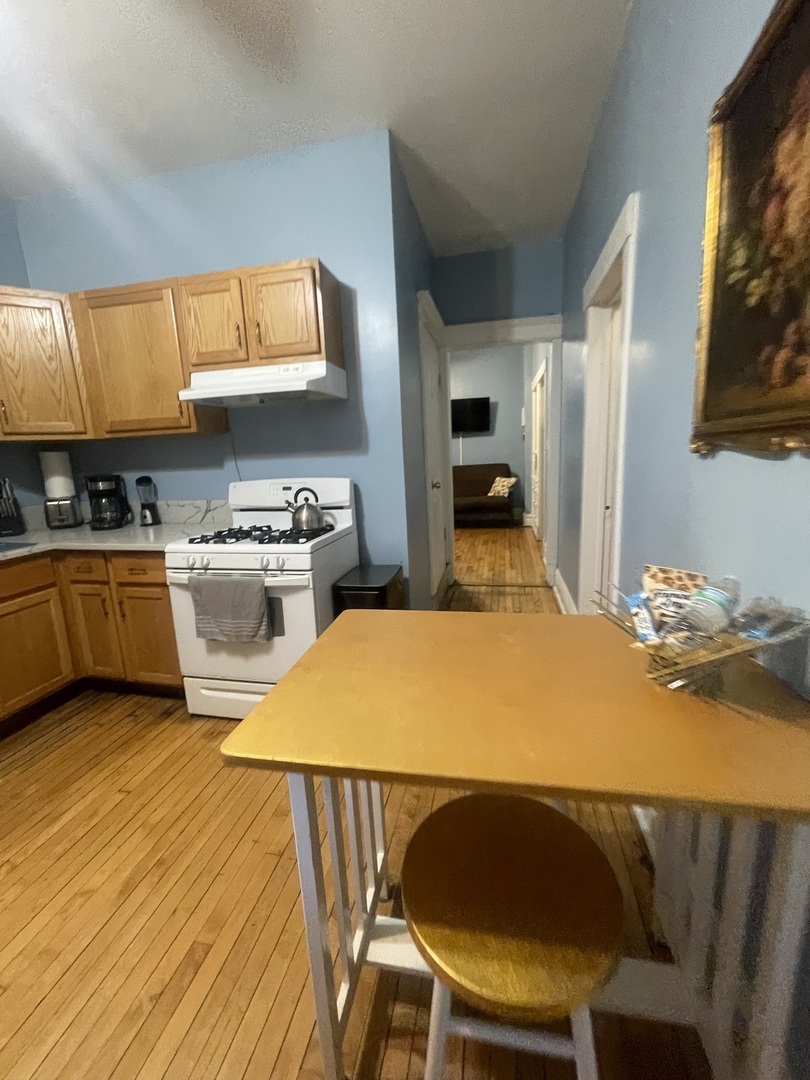 2107 West Coulter Street, Unit 1R Chicago, IL 60608 - Photo 6 of 26 a kitchen with a table chairs a stove and wooden floor