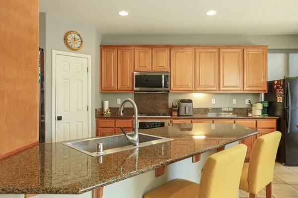 a kitchen with stainless steel appliances granite countertop a refrigerator a stove and a sink with granite countertops