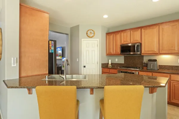 a kitchen with stainless steel appliances granite countertop a stove a sink a refrigerator and a granite counter tops with white cabinets