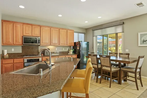 a kitchen with stainless steel appliances granite countertop table chairs sink and cabinets
