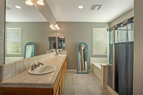 a spacious bathroom with a granite countertop sink a mirror and a shower