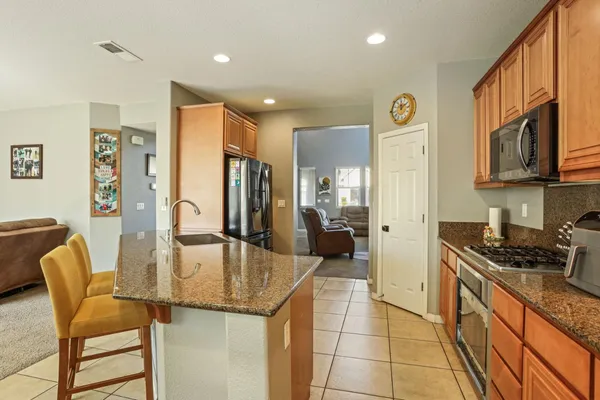 a kitchen with stainless steel appliances granite countertop a stove a refrigerator a dining table and chairs with wooden floor