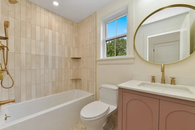 a bathroom with a toilet sink vanity tub and mirror