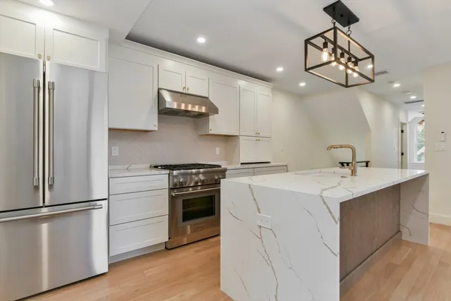 a kitchen with kitchen island white cabinets and stainless steel appliances
