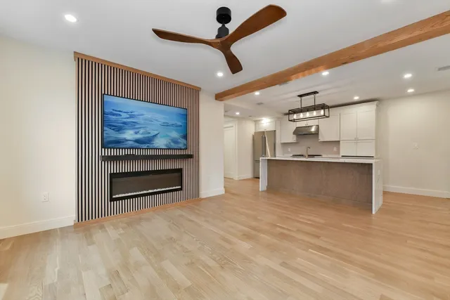 a view of kitchen and empty room with wooden floor