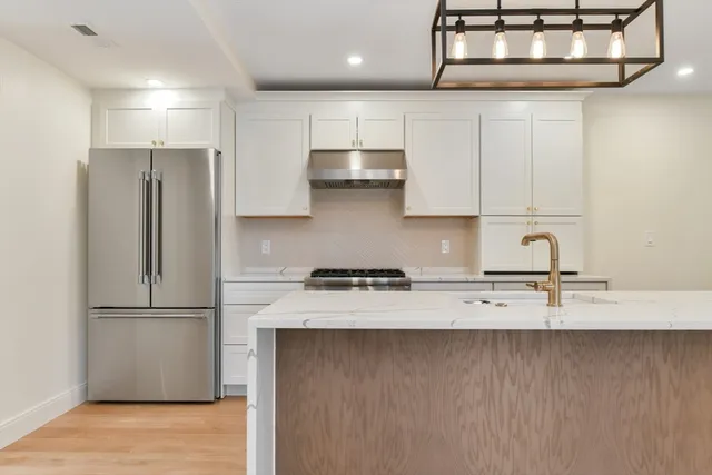 a kitchen with stainless steel appliances granite countertop a refrigerator a sink and a stove