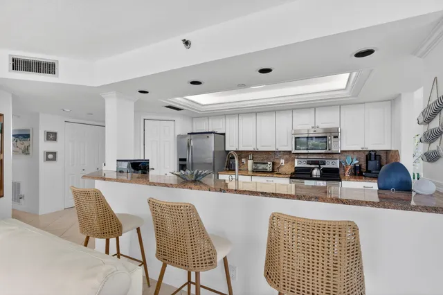 a kitchen with stainless steel appliances kitchen island granite countertop a dining table chairs microwave and sink