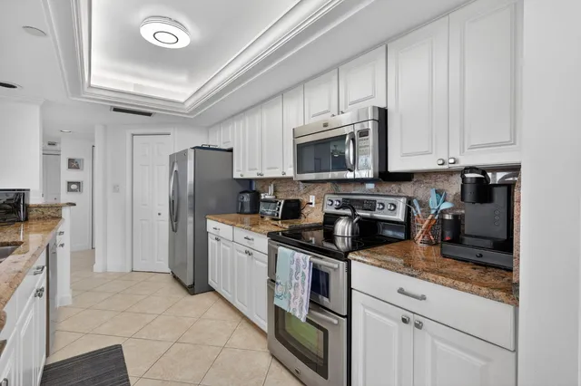 a kitchen with stainless steel appliances granite countertop a stove a sink a refrigerator a microwave and cabinets