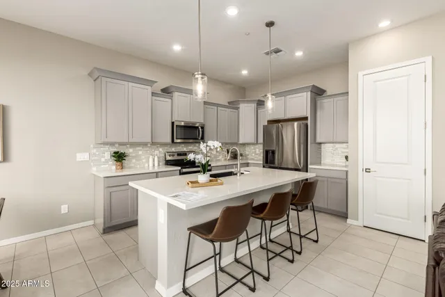 a kitchen with a sink a center island stainless steel appliances and cabinets