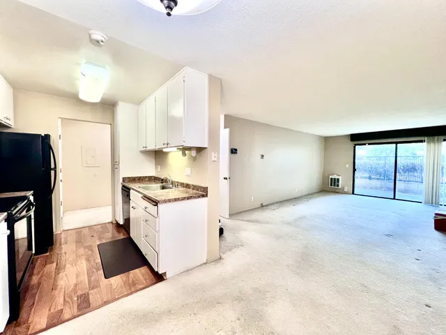 a kitchen with a stove a refrigerator and a sink with wooden floor