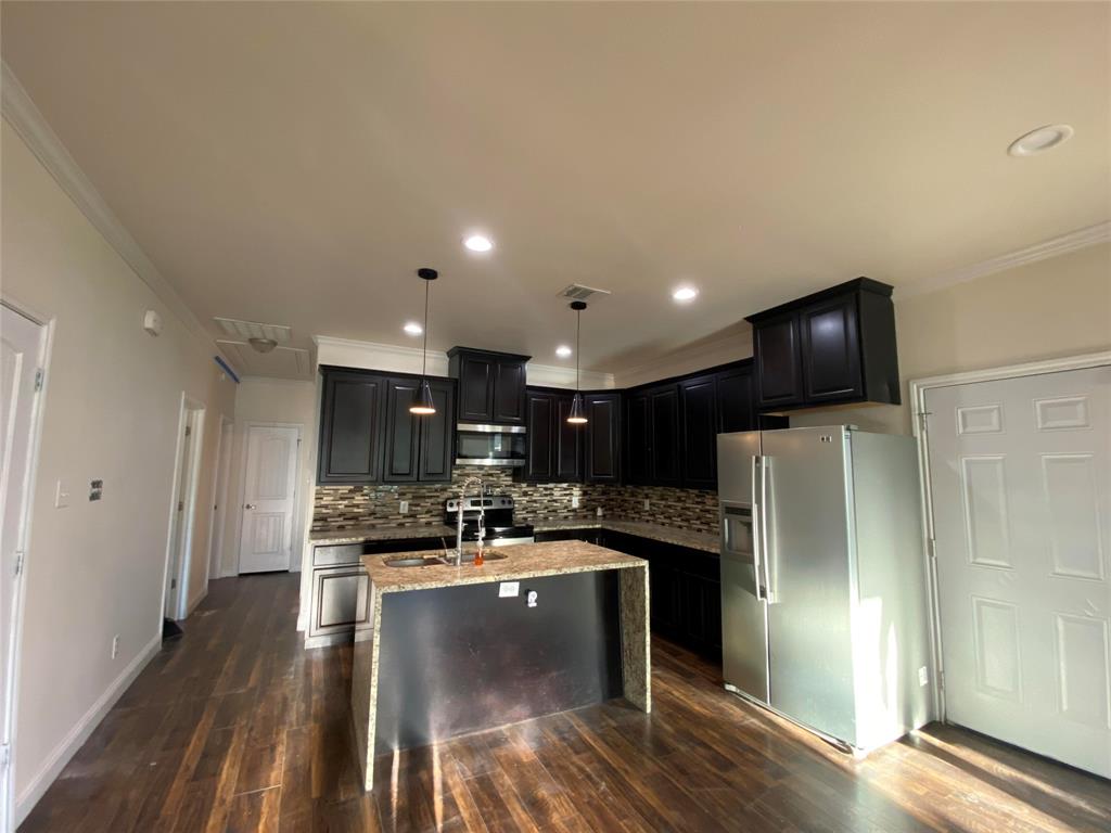 3912 Avant Street Dallas, TX 75215 - Photo 4 of 27 a kitchen with stainless steel appliances granite countertop a refrigerator a stove a sink and a microwave oven with wooden floor