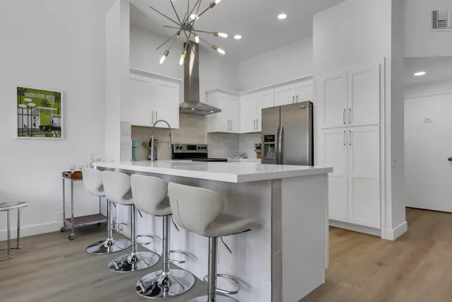 a kitchen with stainless steel appliances a table chairs refrigerator and cabinets