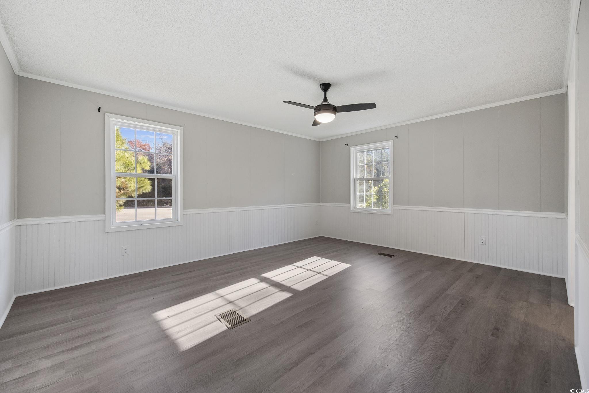 4221 Blake Road Myrtle Beach, SC 29588 - Photo 15 of 36 Empty room with dark wood-style flooring, crown molding, and a ceiling fan