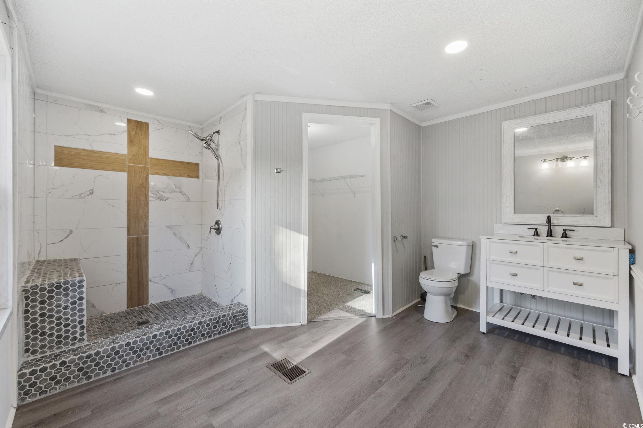 4221 Blake Road Myrtle Beach, SC 29588 - Photo 17 of 36 Bathroom with vanity, crown molding, a spacious closet, a marble finish shower, and wood finished floors