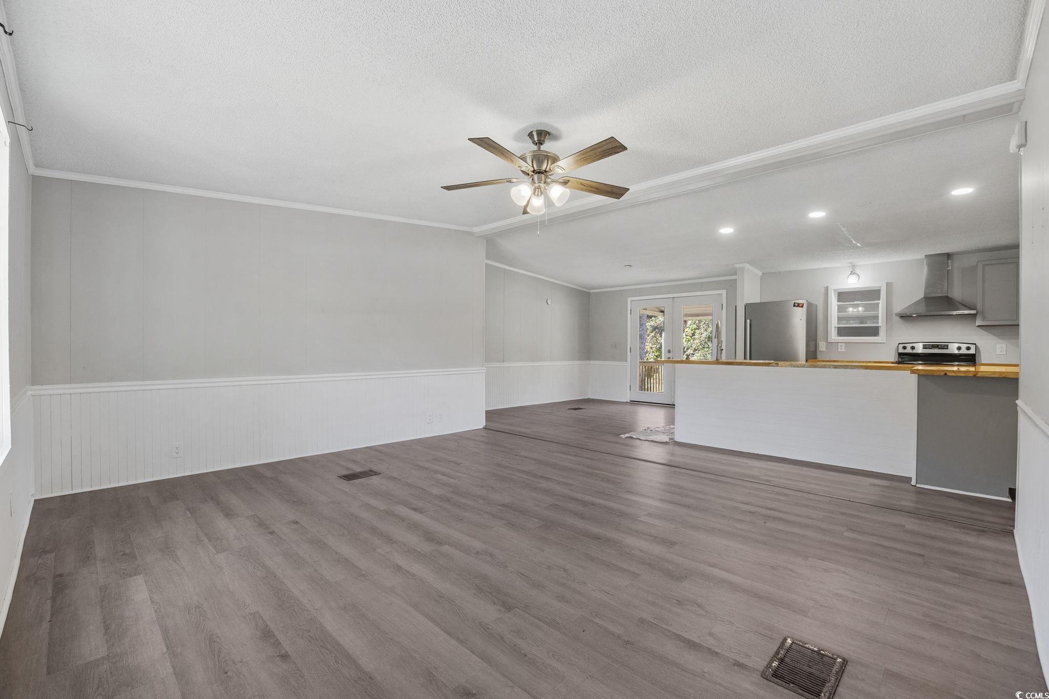 4221 Blake Road Myrtle Beach, SC 29588 - Photo 2 of 36 Unfurnished living room with dark wood finished floors, french doors, a wainscoted wall, crown molding, and a ceiling fan