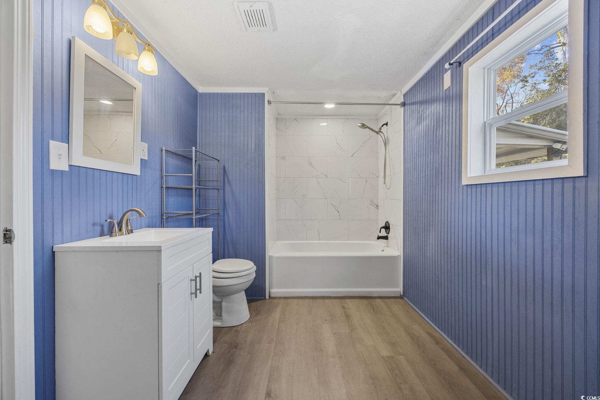 4221 Blake Road Myrtle Beach, SC 29588 - Photo 22 of 36 Bathroom featuring light wood-type flooring, shower / bath combo with shower curtain, vanity, crown molding, and wooden walls