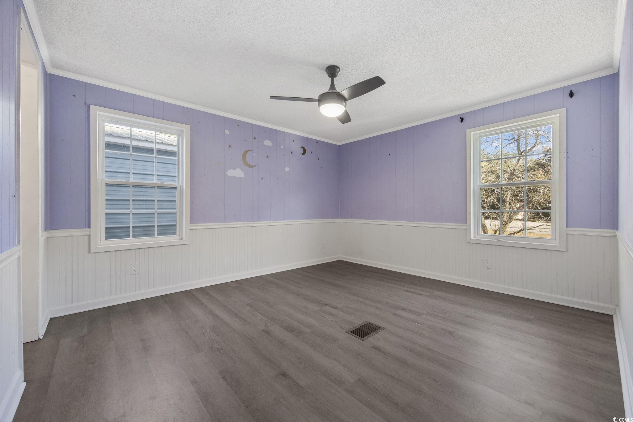 4221 Blake Road Myrtle Beach, SC 29588 - Photo 23 of 36 Unfurnished room featuring crown molding, dark wood-style floors, wood walls, a ceiling fan, and a textured ceiling